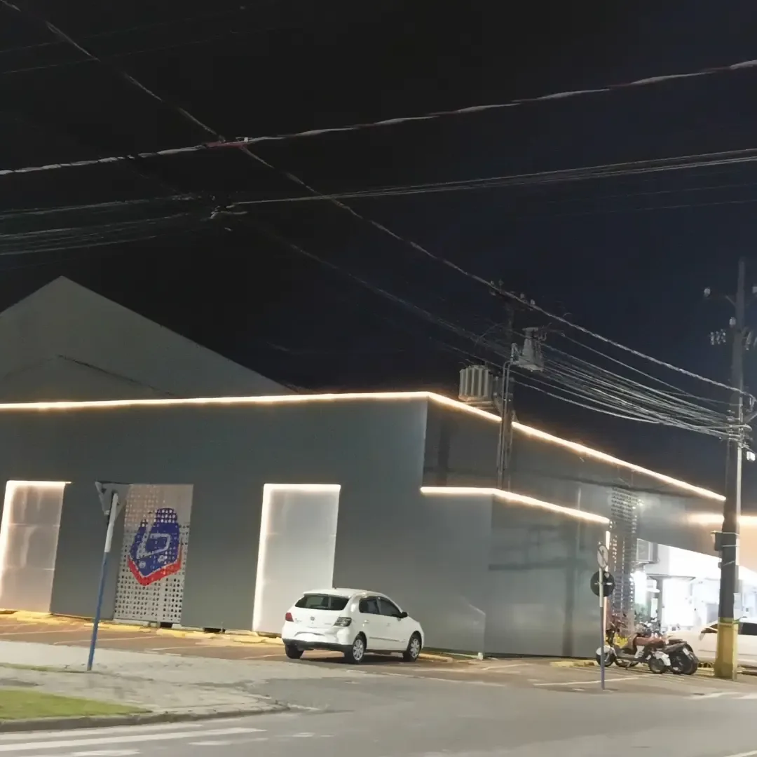 Iluminação perimetral em fachada comercial noturna
